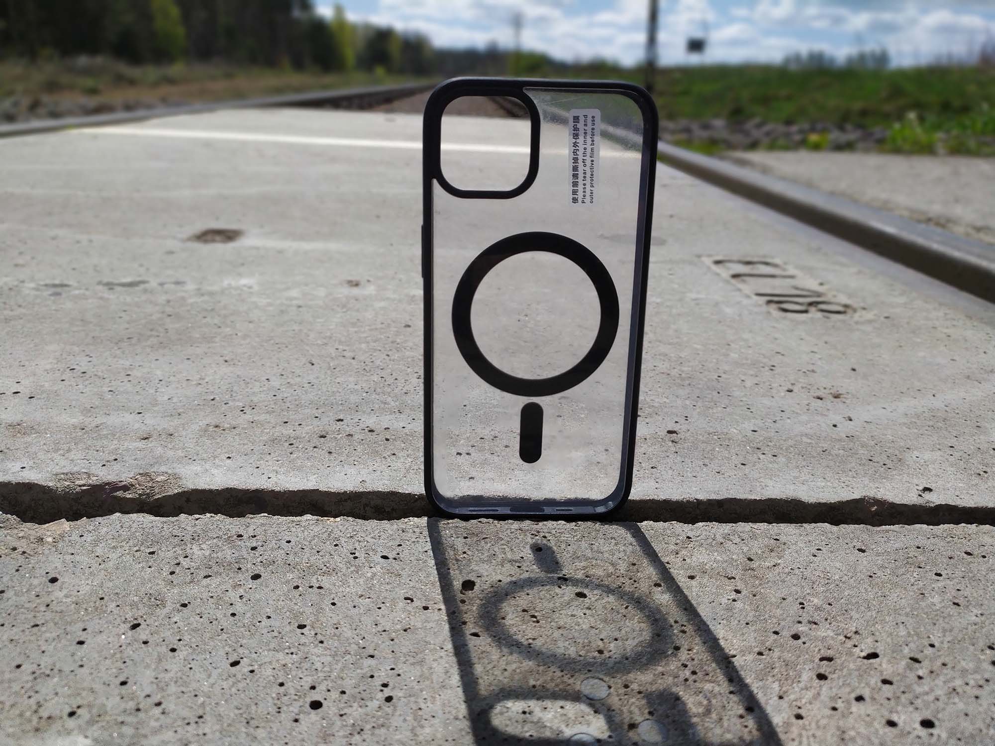 Etui z serii Clear+ Case z MagSafe pokazane od tyłu na torach kolejowych.
