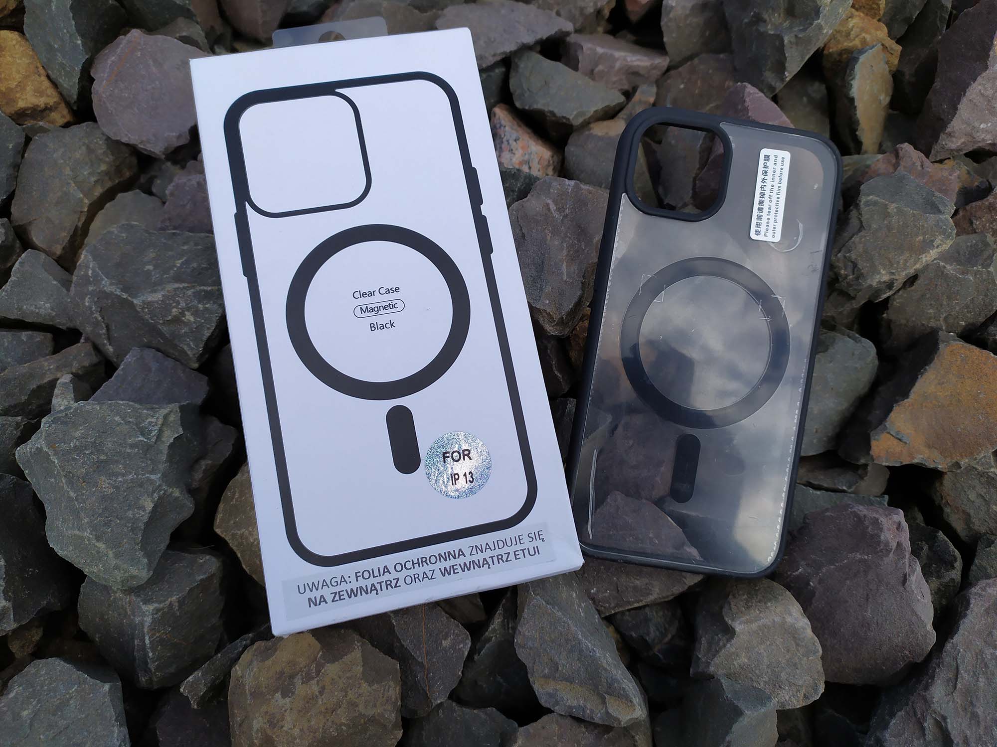 Etui z serii Clear+ Case z MagSafe z pudełkiem umieszczone wśród kamieni.